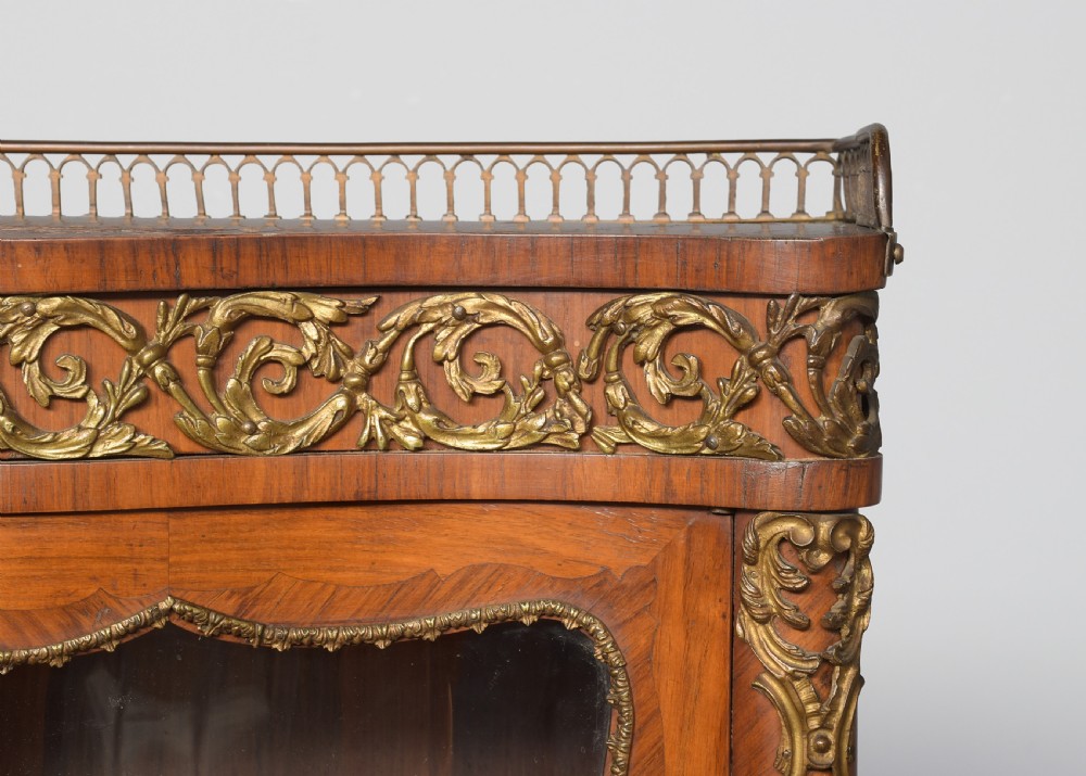A nineteenth-century French style kingwood and walnut writing desk featuring an upper glazed display cabinet, brass top gallery, cabriole legs, and gilded metal mounts. View IX