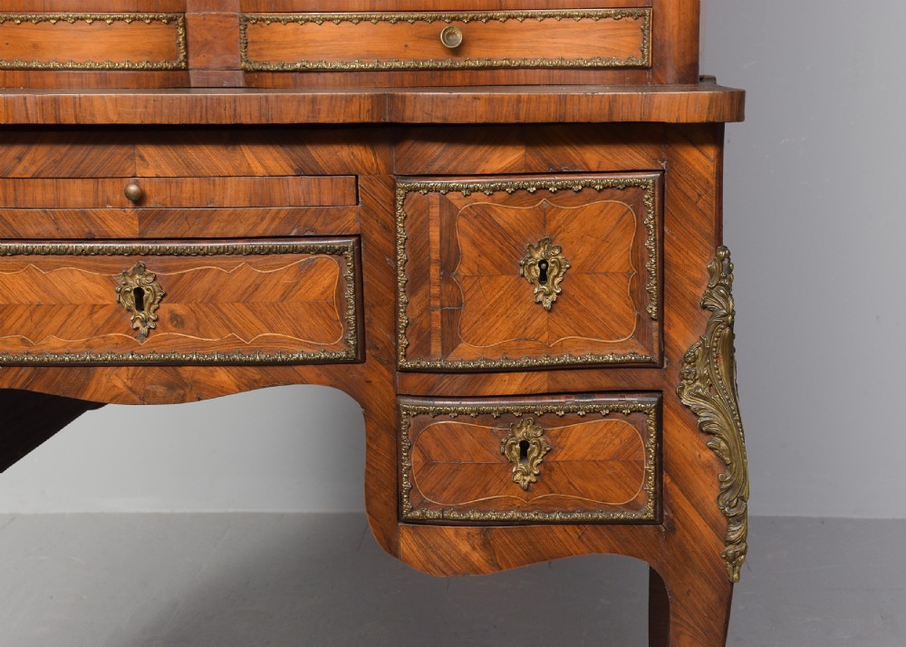 A nineteenth-century French style kingwood and walnut writing desk featuring an upper glazed display cabinet, brass top gallery, cabriole legs, and gilded metal mounts. View X