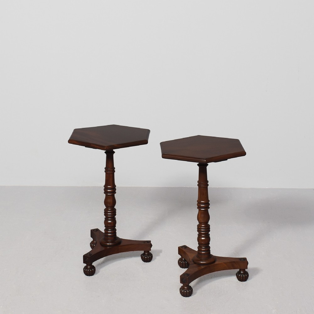 A pair of dark mahogany William IV wine tables featuring hexagonal tops, turned column pedestals, and triform bases.