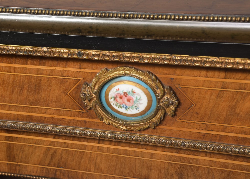 A pair of Victorian burr walnut pier cabinets with single glazed doors, ebonised trim, ormolu corner mounts, and oval porcelain plaques. View VII