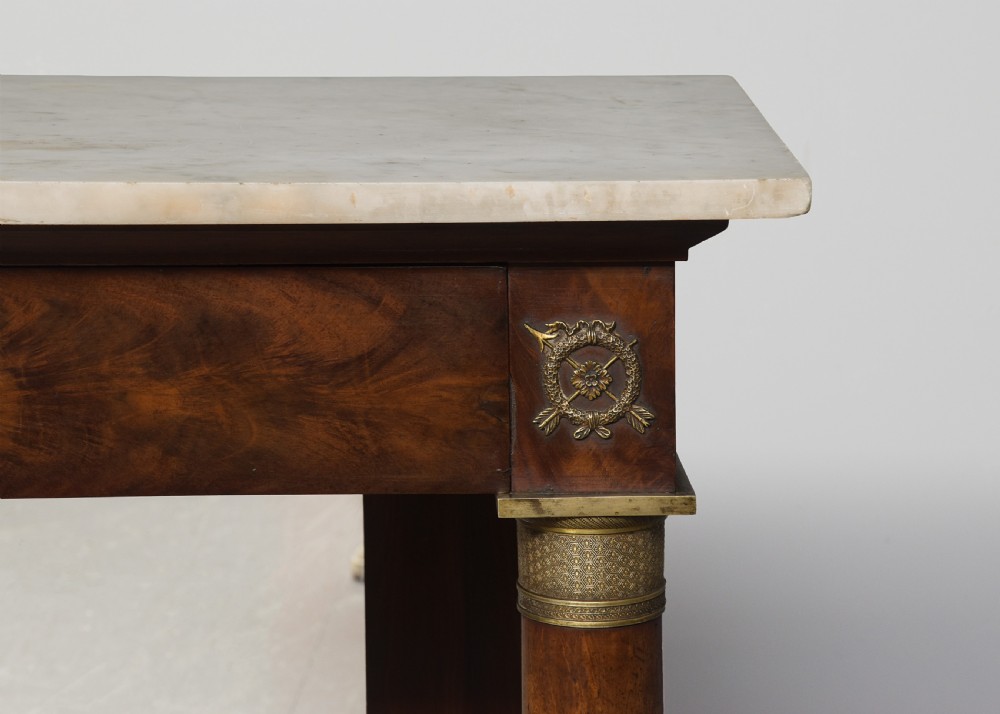 An early nineteenth-century French Empire mahogany console table featuring a light marble top, gilt brass column mounts, a mirrored back panel, and a lower shelf. View VIII