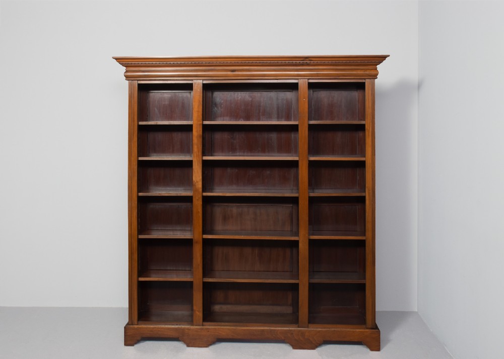 A tall mid-Victorian mahogany three-section open bookcase featuring a moulded top cornice and a solid plinth base filled with books. View VIII