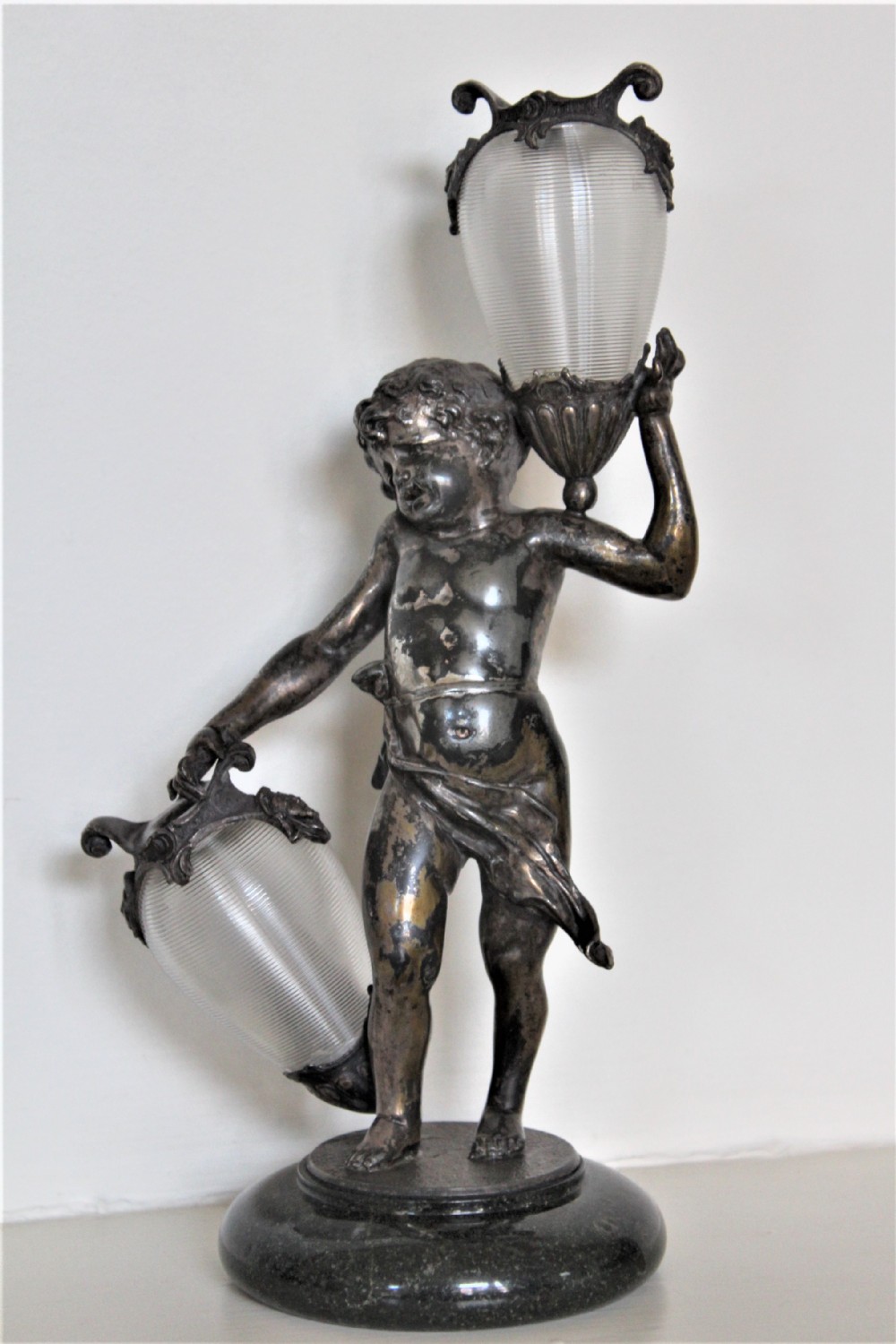 A delightful garniture of three chubby cherubs holding finely ribbed glass vases on marble French Circa 1900