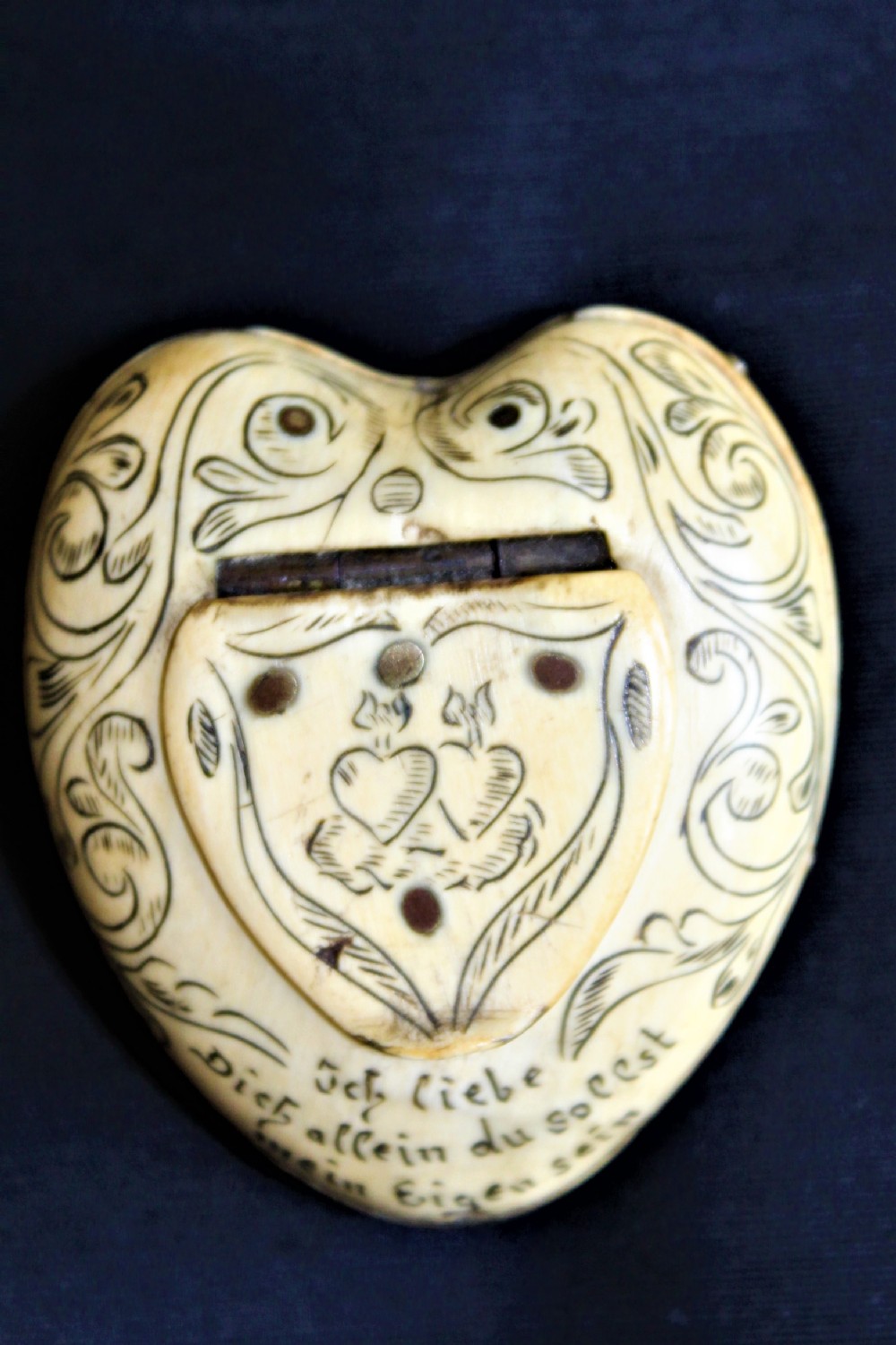 A charming 19th century small bone heart shaped trinket box with inscribed ink decoration of flowers and lovers to the reverse