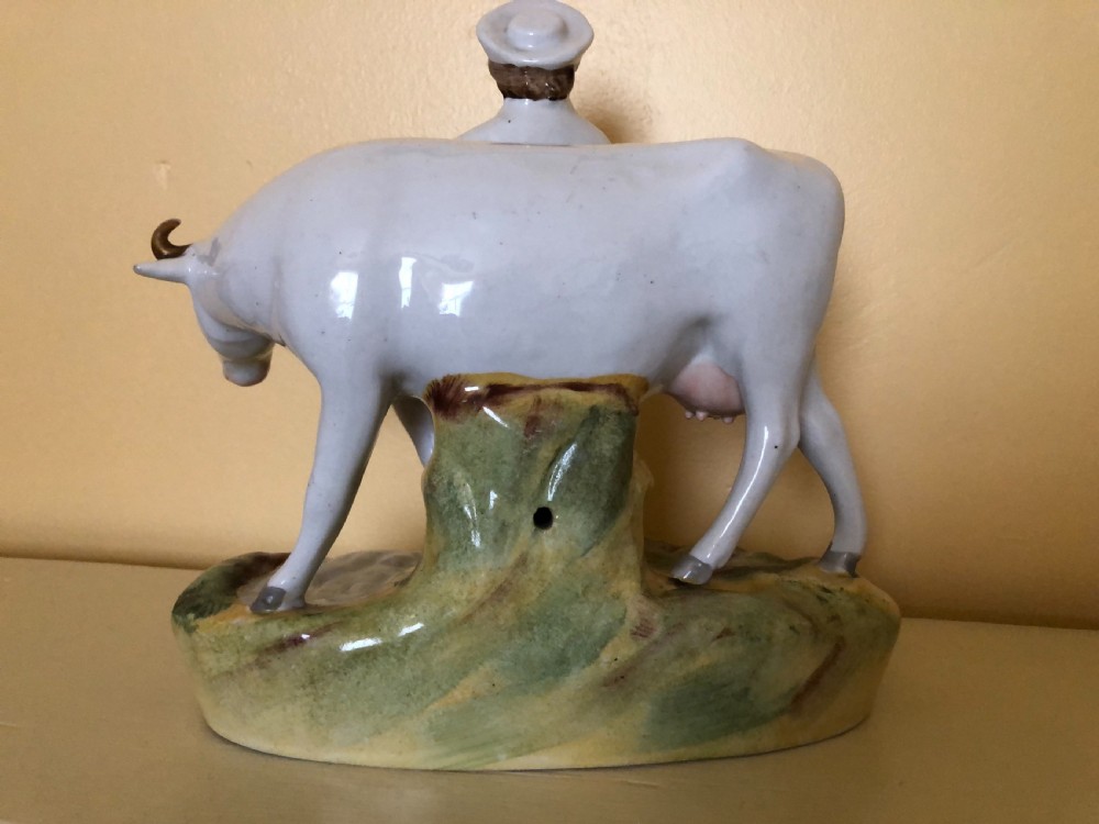 A pair of Victorian Staffordshire ceramic figures featuring a boy standing beside a white cow on one base, and a milkmaid with a pail beside a cow on the other base. View II