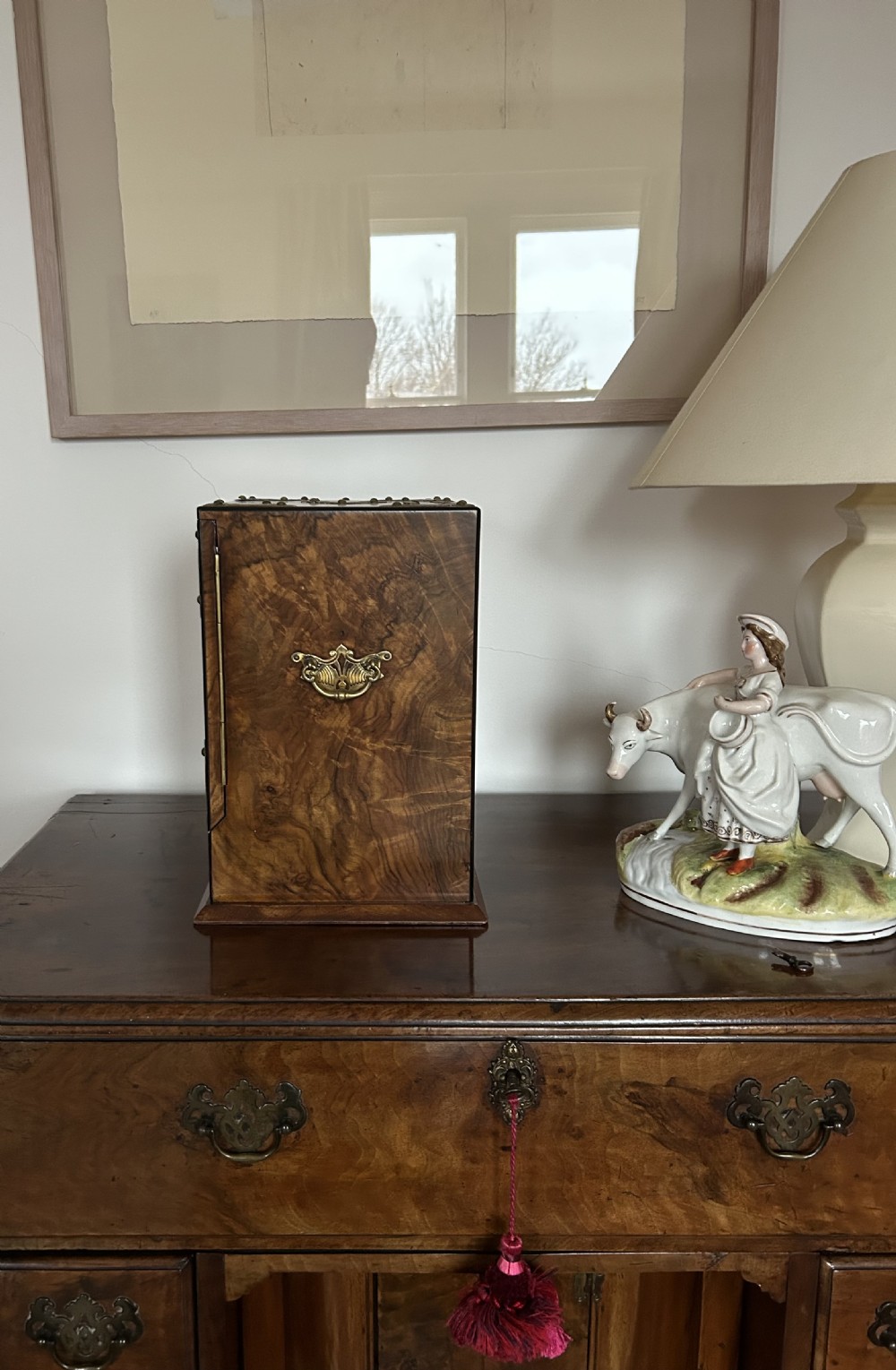 A Victorian burr walnut cigar cabinet featuring two doors adorned with pierced brass corner brackets and a central lock mechanism above a lower drawer. View II