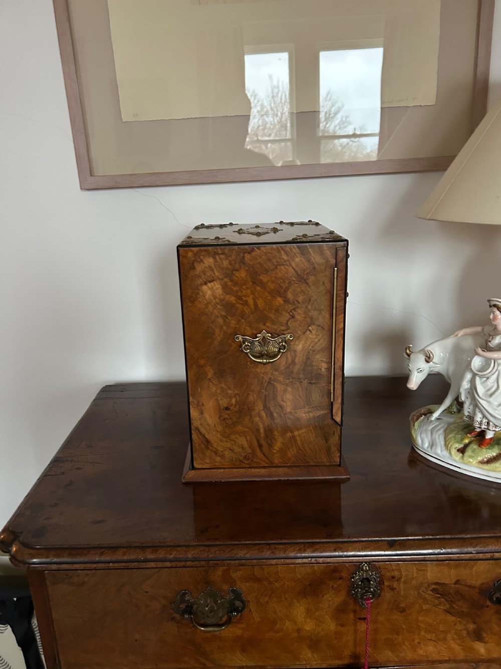 A Victorian burr walnut cigar cabinet featuring two doors adorned with pierced brass corner brackets and a central lock mechanism above a lower drawer. View III