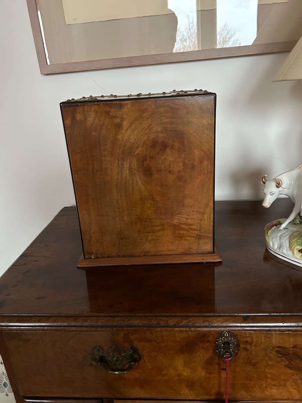 A Victorian burr walnut cigar cabinet featuring two doors adorned with pierced brass corner brackets and a central lock mechanism above a lower drawer. View V
