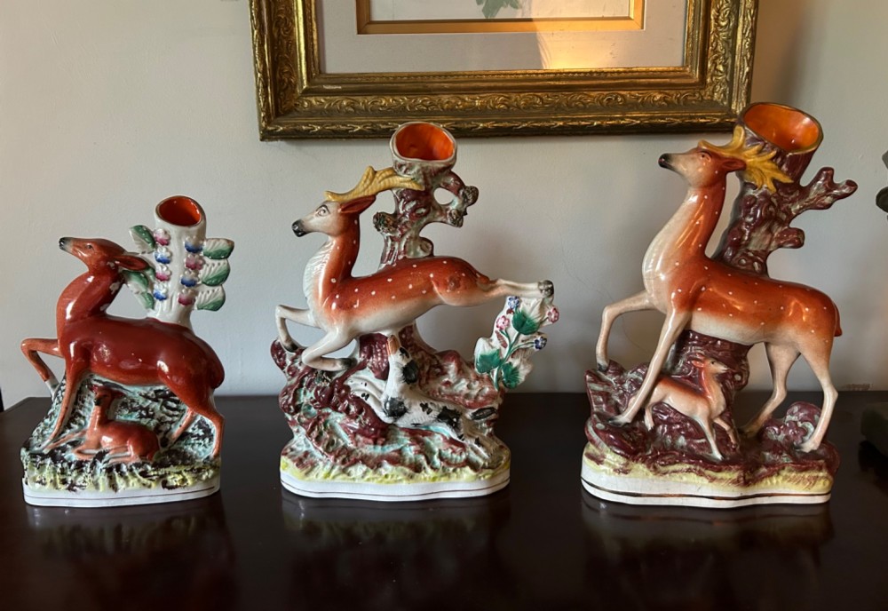 Three 19th-century Staffordshire earthenware spill vases moulded in the form of deer, featuring hand-painted enamels on tree-trunk bases.