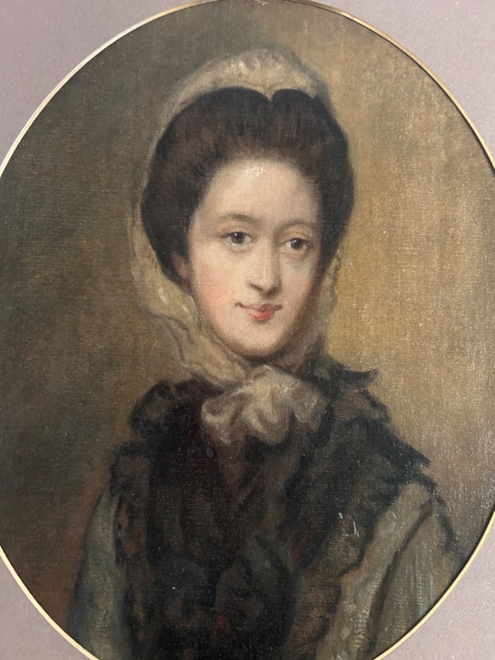 A late eighteenth-century oval oil portrait depicting a woman wearing a bonnet and dark mantle, presented inside a gilded frame. View III