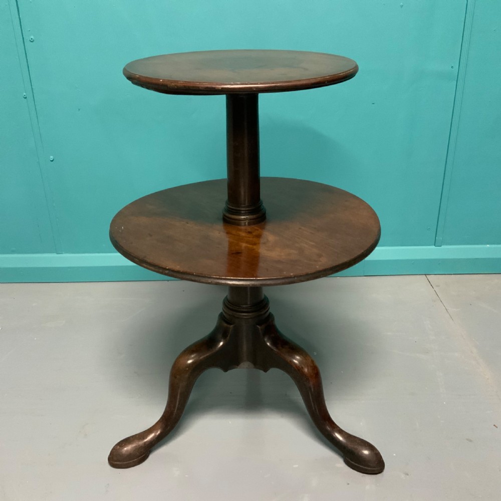 A George II mahogany two-tier dumb waiter with graduated circular surfaces, a turned central column, and a tripod base.