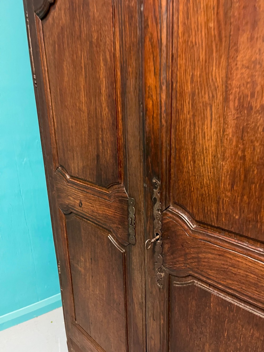 An 18th-century low French oak armoire featuring two fielded panel doors, carved frieze details, and long iron exterior hinges. View V