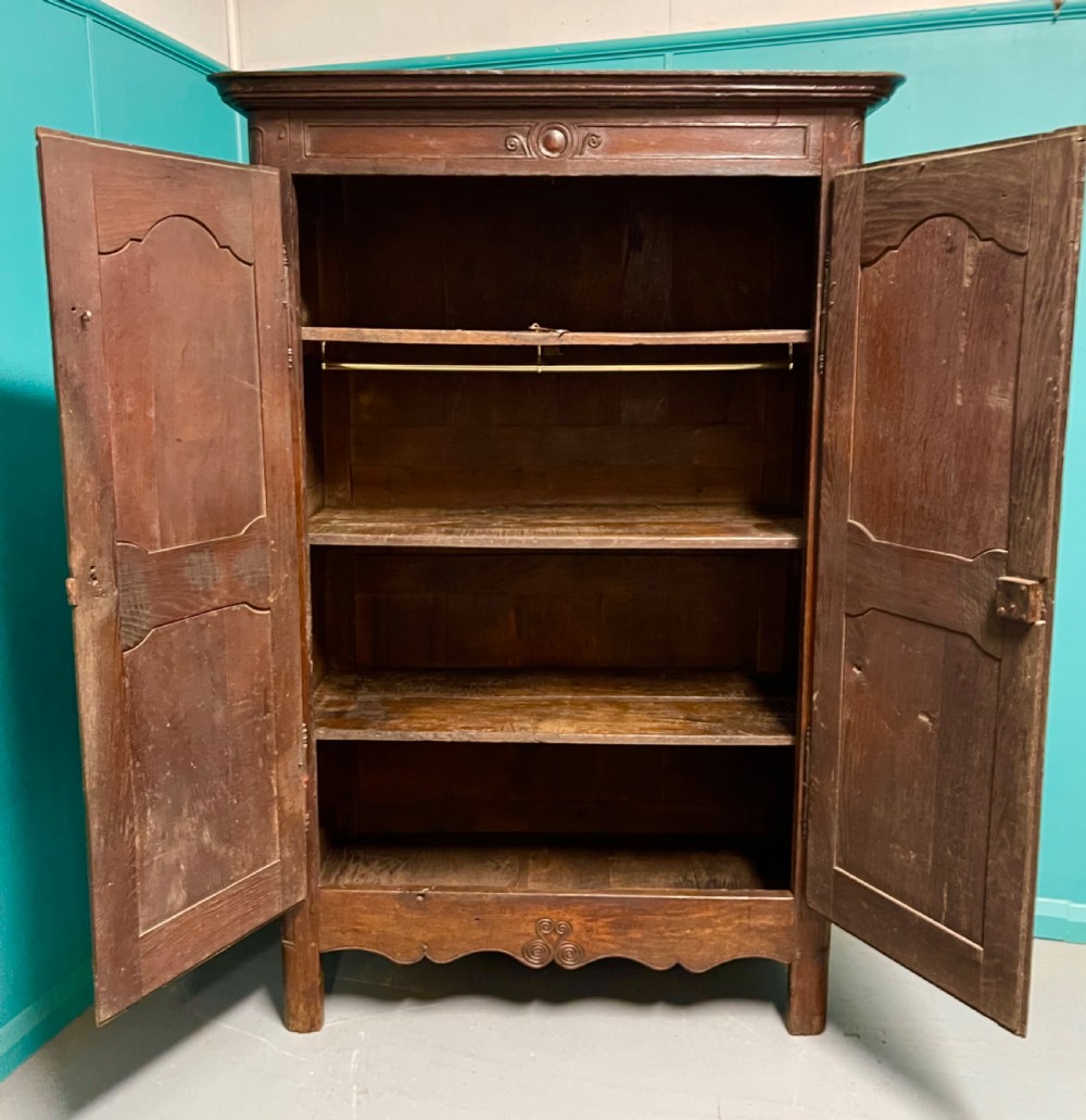 An 18th-century low French oak armoire featuring two fielded panel doors, carved frieze details, and long iron exterior hinges. View VII
