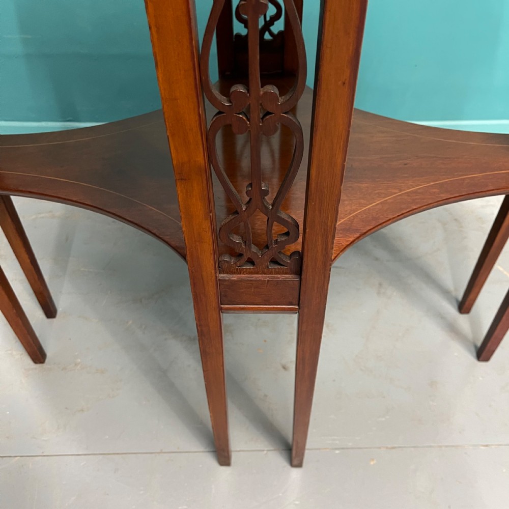 An Edwardian oval wooden side table featuring a central floral marquetry medallion, crossbanded border, pierced fretwork side aprons, and an under-shelf. View IV