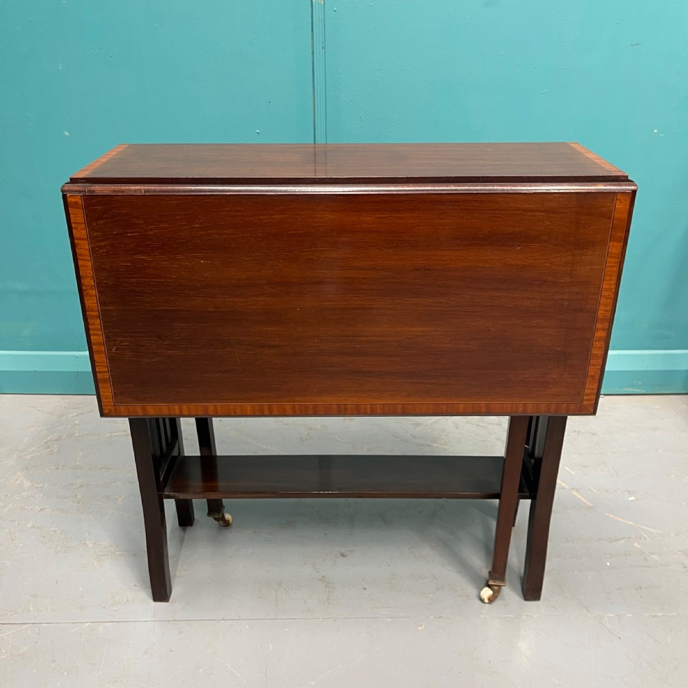 An Edwardian dark mahogany drop-leaf Sutherland table featuring satinwood crossbanding around the tabletop edge and slender gate-leg supports. View II