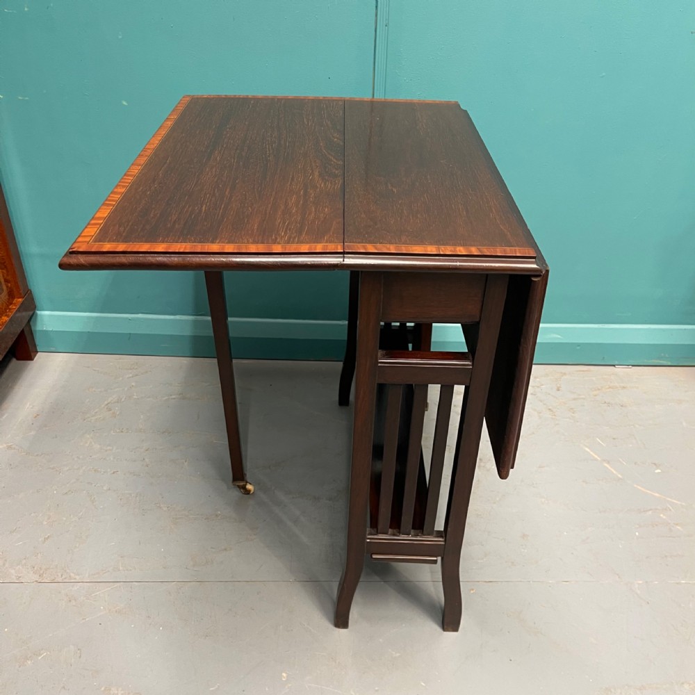An Edwardian dark mahogany drop-leaf Sutherland table featuring satinwood crossbanding around the tabletop edge and slender gate-leg supports. View IV