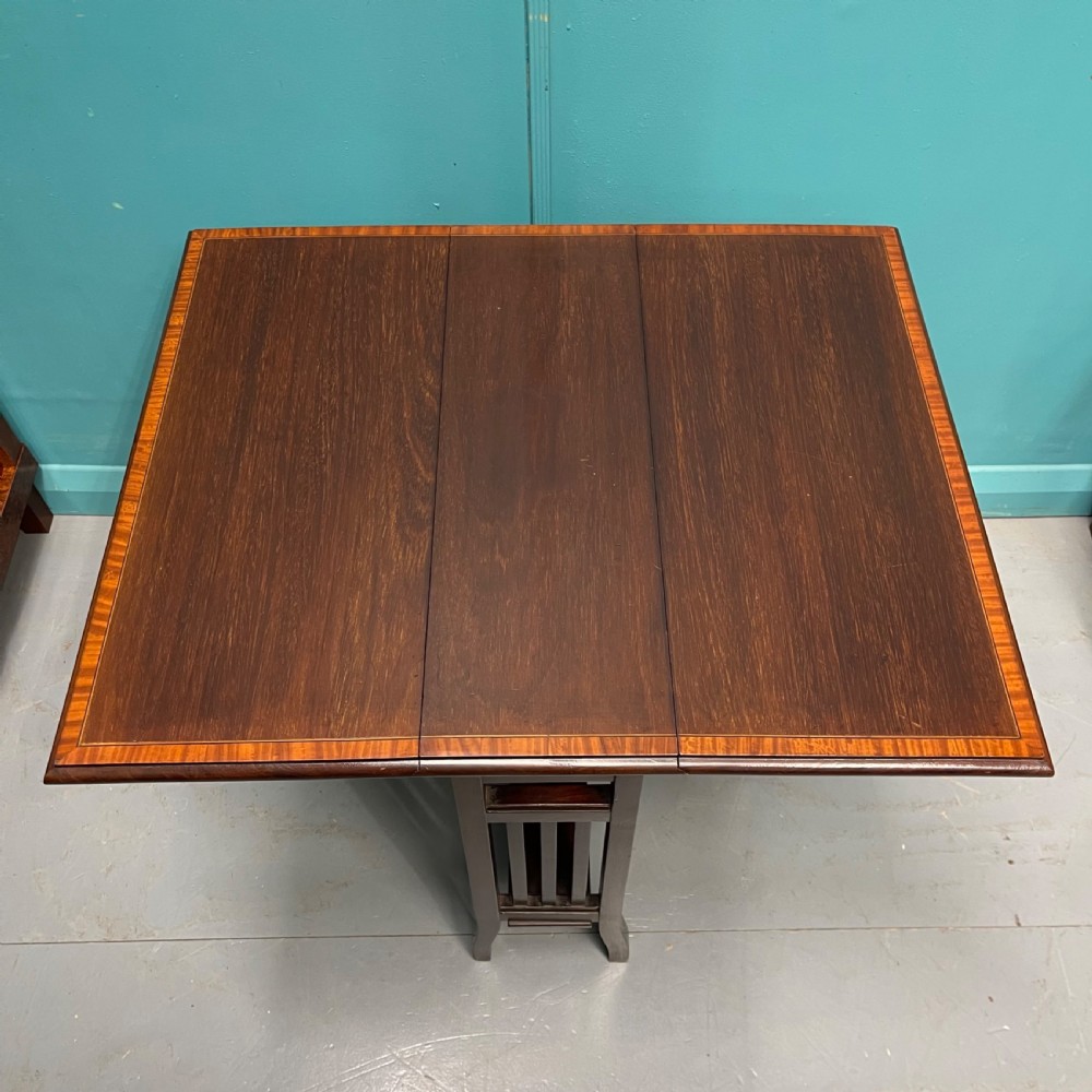 An Edwardian dark mahogany drop-leaf Sutherland table featuring satinwood crossbanding around the tabletop edge and slender gate-leg supports. View VI
