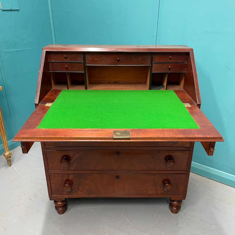 An early Victorian mahogany writing bureau with an open sloping flap revealing a green writing surface and internal pigeonholes, resting on turned feet. View II