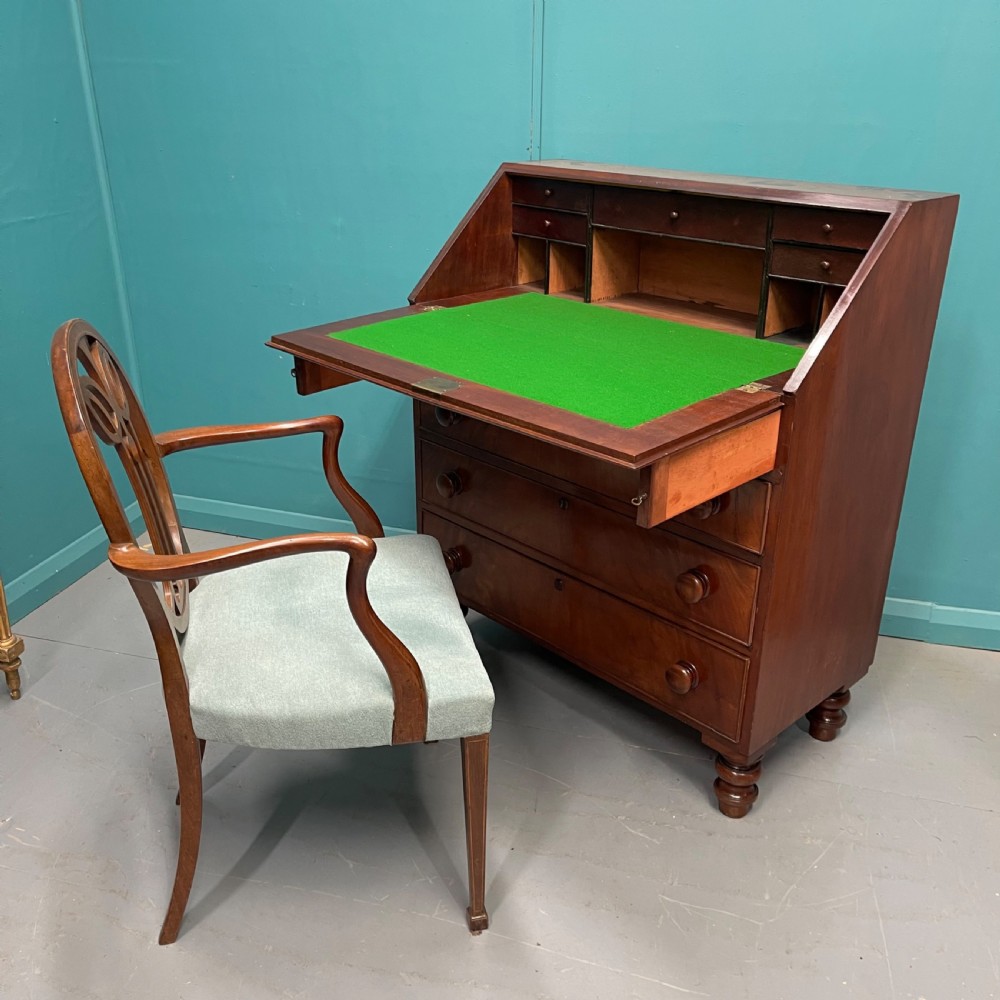 An early Victorian mahogany writing bureau with an open sloping flap revealing a green writing surface and internal pigeonholes, resting on turned feet. View III