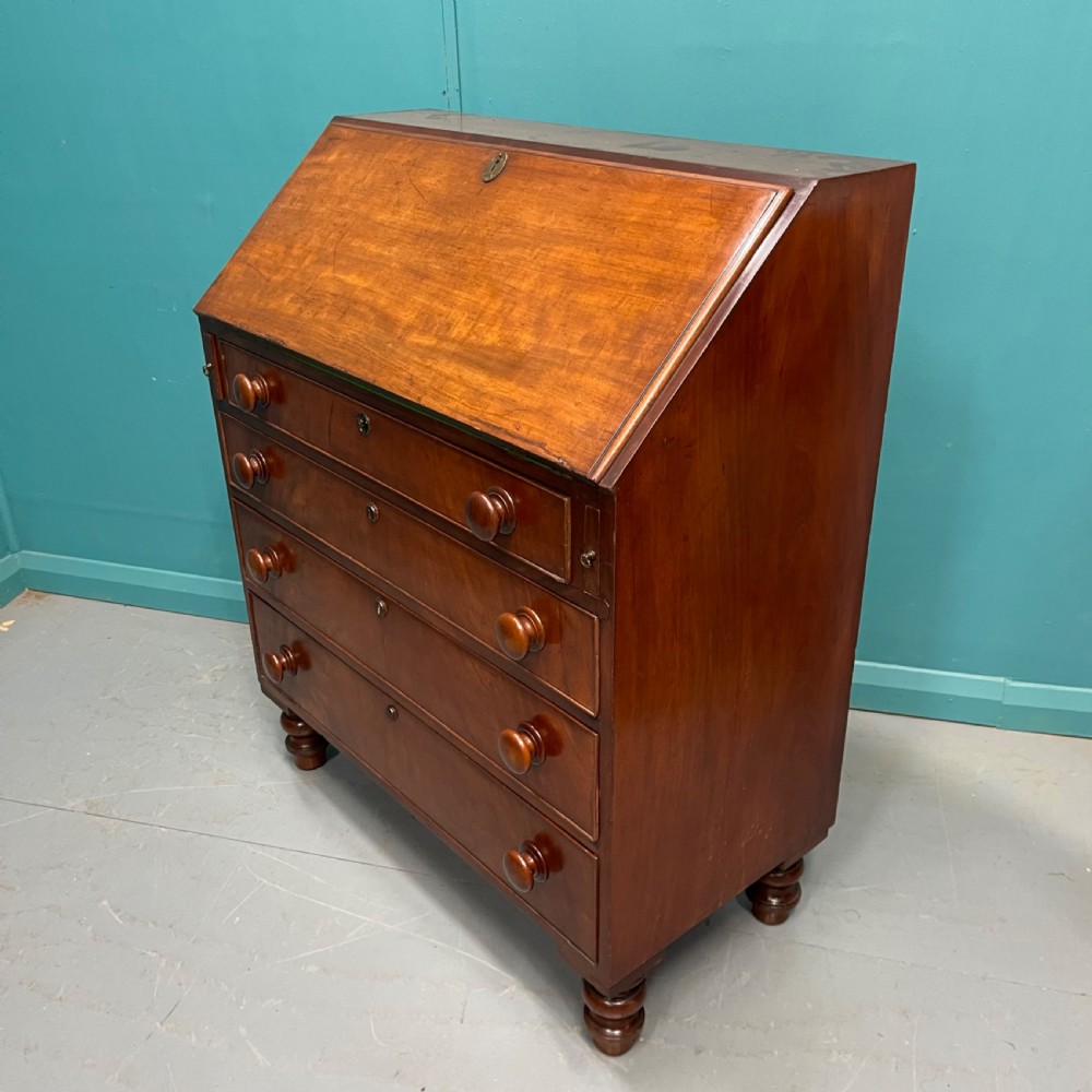 An early Victorian mahogany writing bureau with an open sloping flap revealing a green writing surface and internal pigeonholes, resting on turned feet. View VI