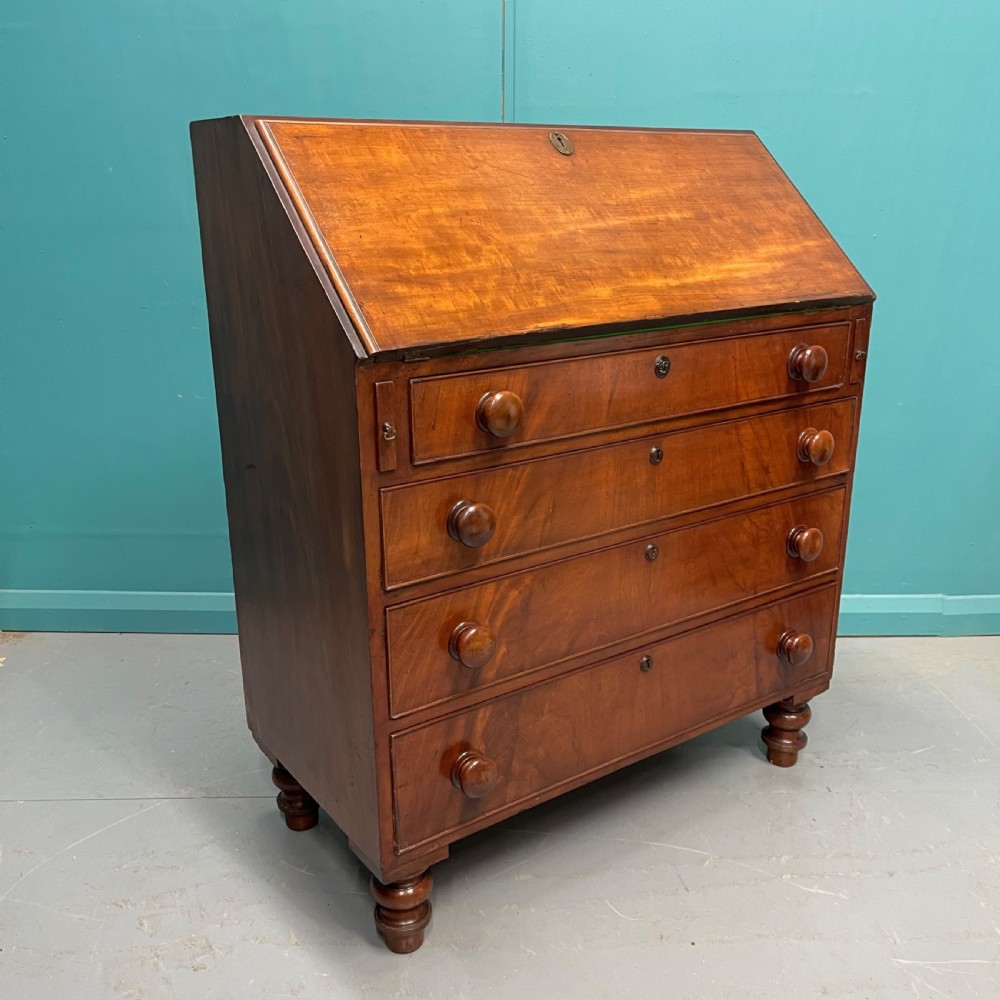 An early Victorian mahogany writing bureau with an open sloping flap revealing a green writing surface and internal pigeonholes, resting on turned feet. View VII