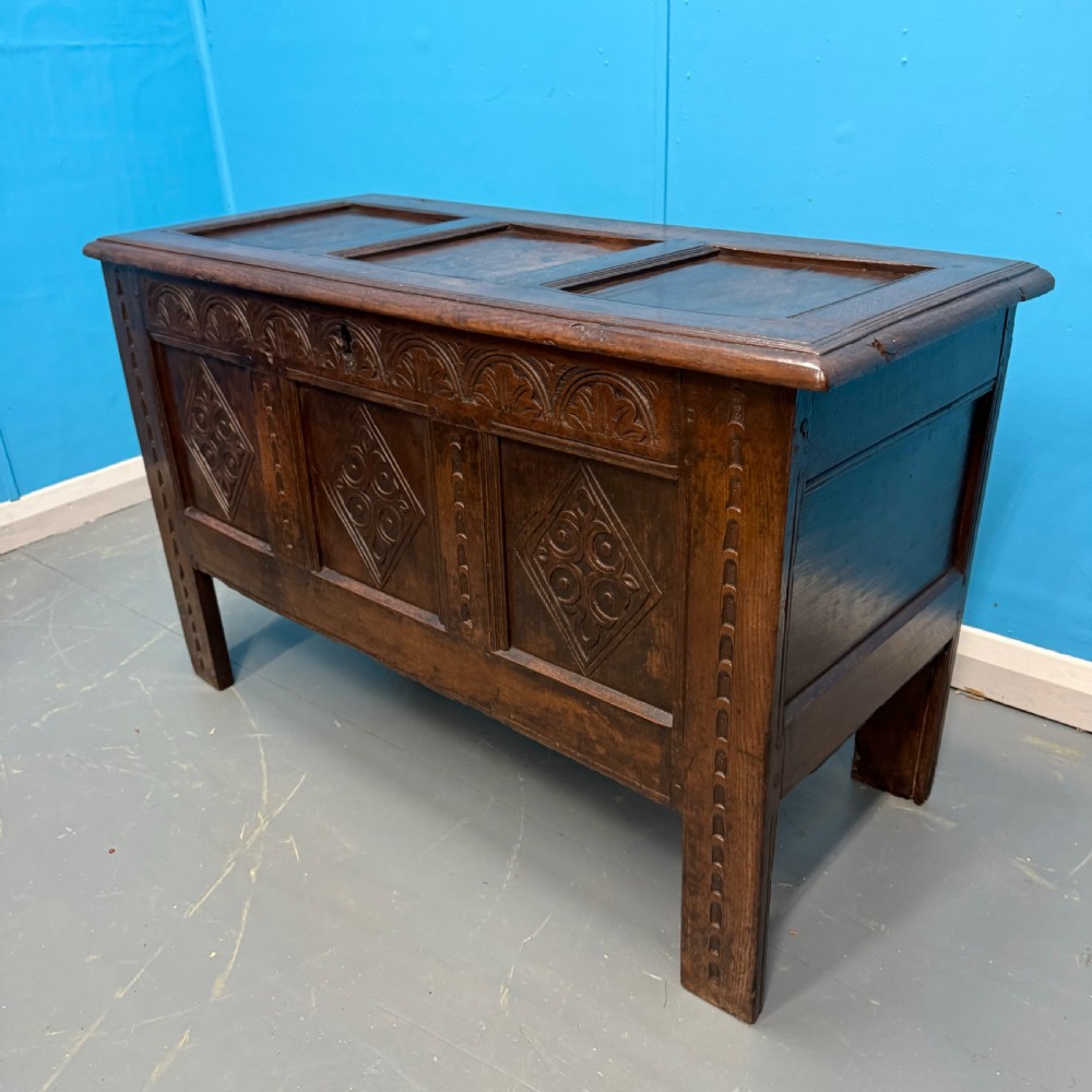 An 18th-century dark oak coffer featuring three carved diamond lozenge panels, an arcaded top rail, and a panelled hinged lid. View II