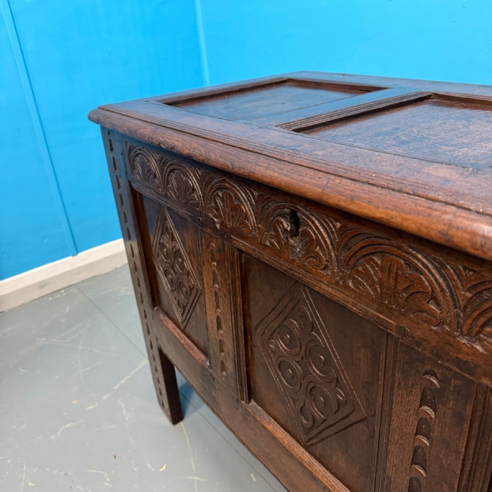 An 18th-century dark oak coffer featuring three carved diamond lozenge panels, an arcaded top rail, and a panelled hinged lid. View IV