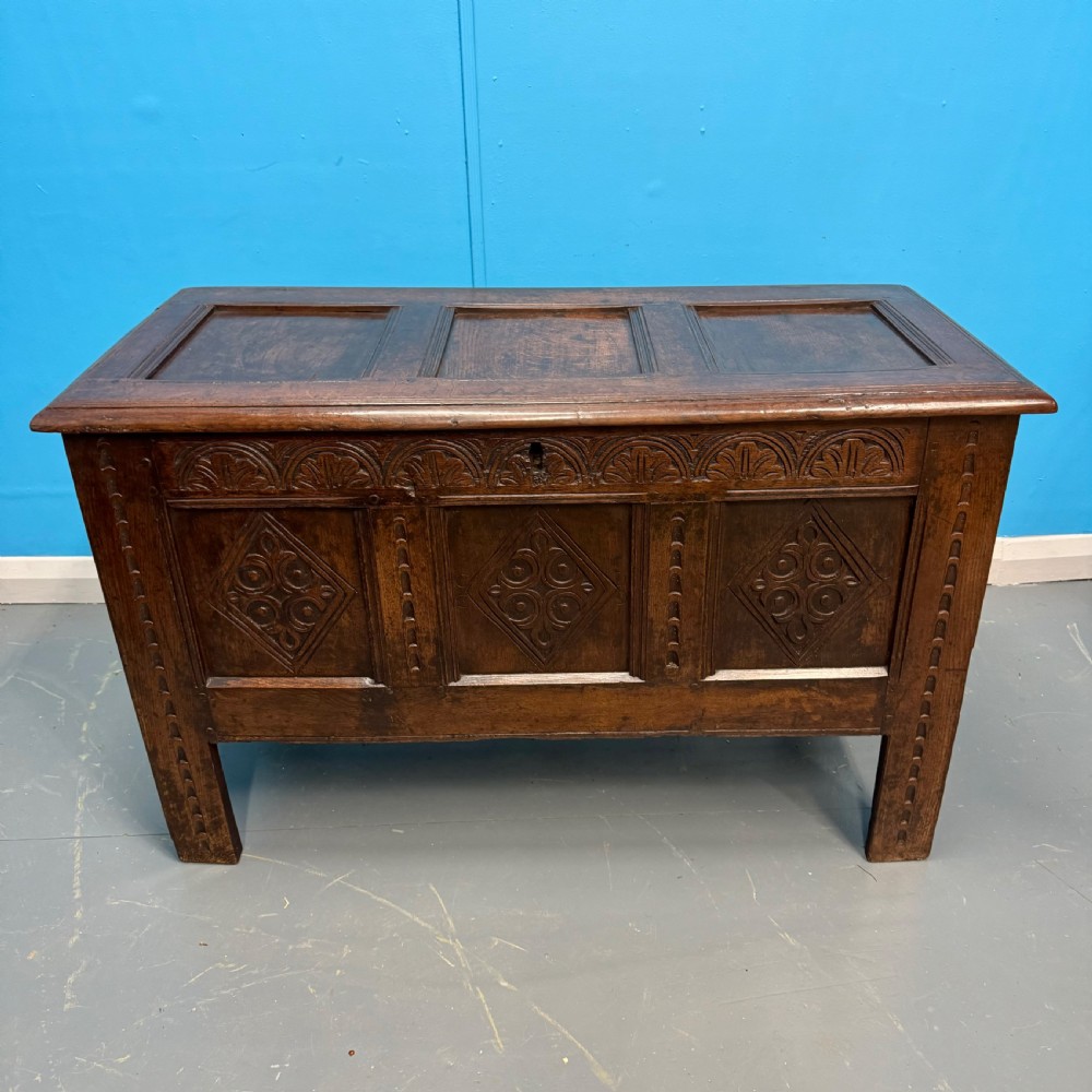 An 18th-century dark oak coffer featuring three carved diamond lozenge panels, an arcaded top rail, and a panelled hinged lid. View VI