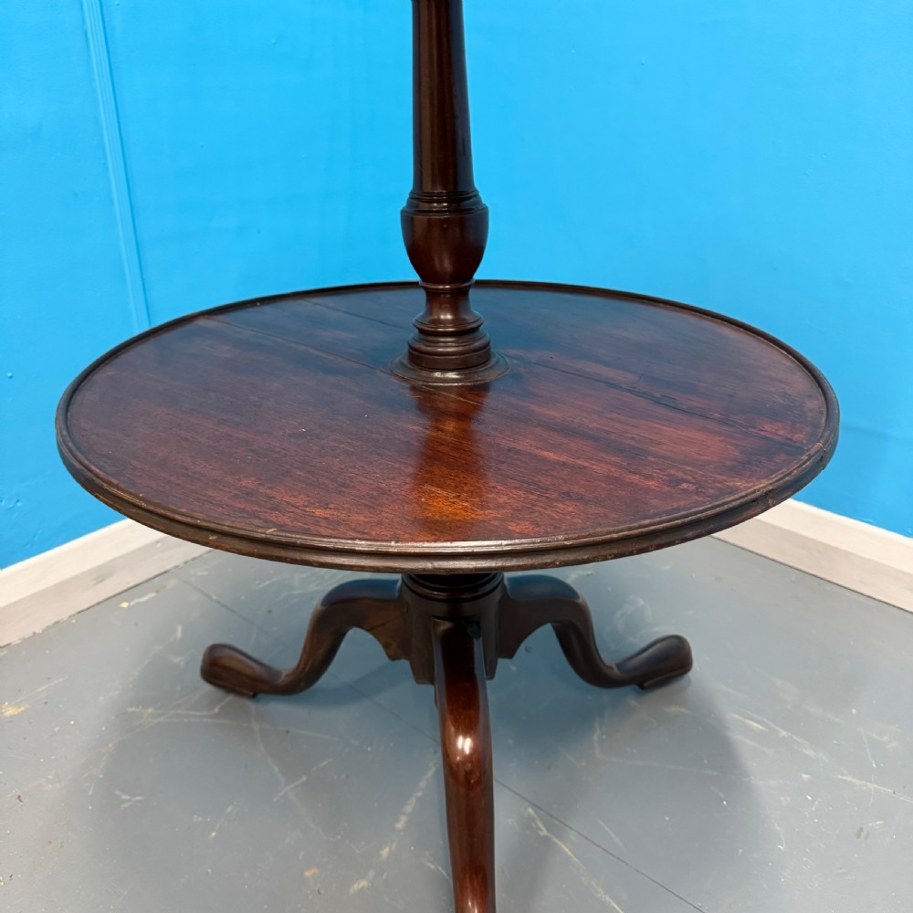 An 18th-century Georgian mahogany two-tier dumb waiter featuring circular tray surfaces, a central turned column, and a tripod base with castors. View III
