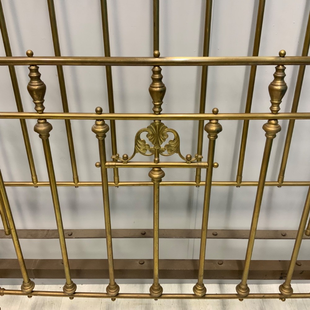 Victorian 5ft king-size brass bed frame featuring vertical spindles, turned finials, and a central cast decorative motif alongside original side rails. View II