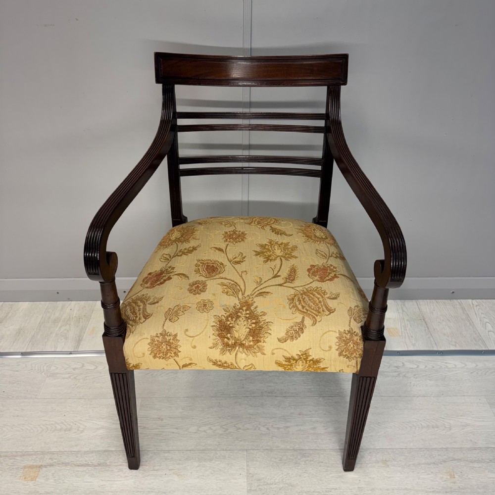 A dark mahogany Regency carver armchair featuring reeded scrolled arms, horizontal slat backrest, fluted front legs, and a golden floral patterned upholstered seat. View IV