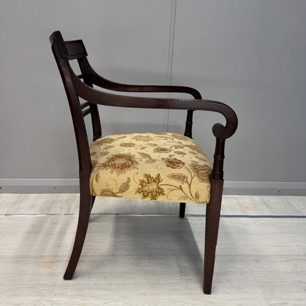 A dark mahogany Regency carver armchair featuring reeded scrolled arms, horizontal slat backrest, fluted front legs, and a golden floral patterned upholstered seat. View VI