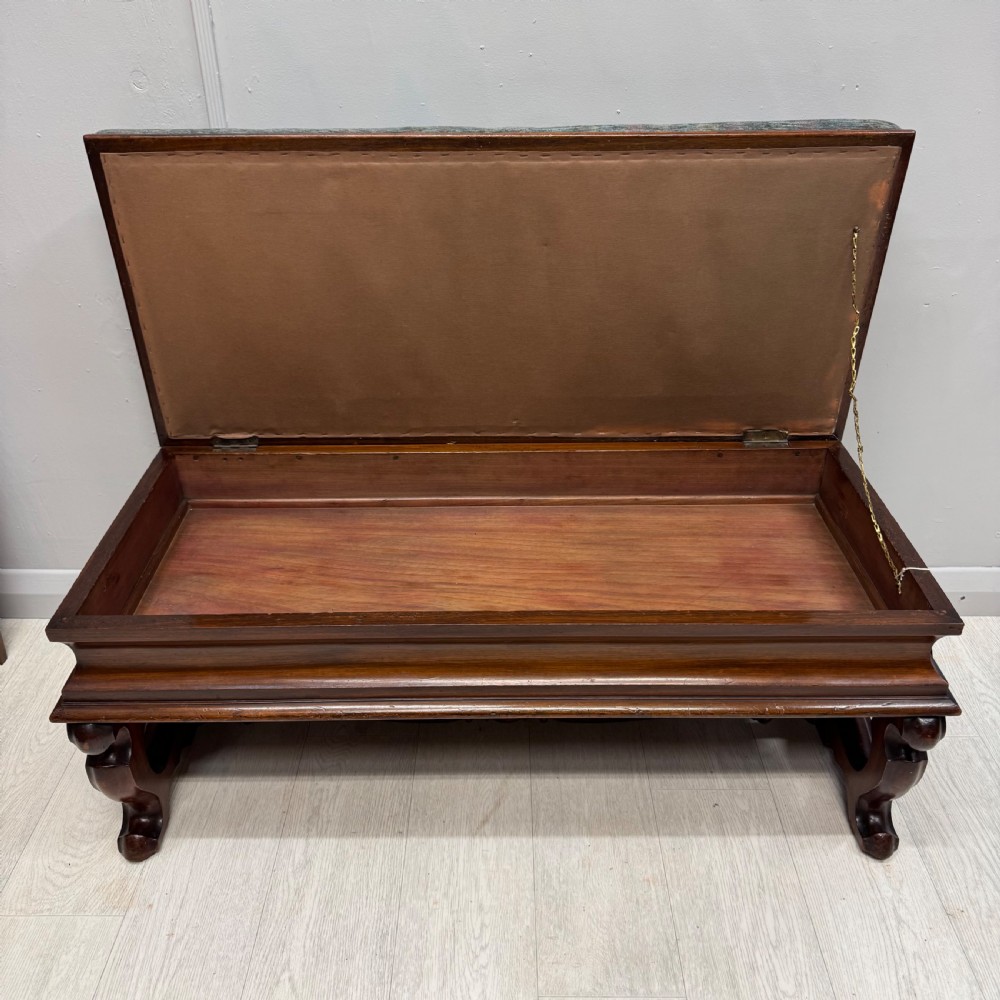 A Victorian mahogany piano duet stool featuring a patterned upholstered hinged top, brass studding, carved cabriole legs, and a turned stretcher base. View II