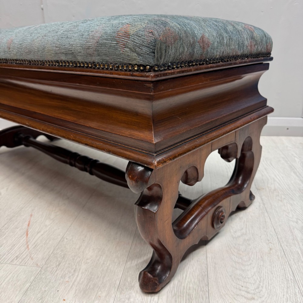 A Victorian mahogany piano duet stool featuring a patterned upholstered hinged top, brass studding, carved cabriole legs, and a turned stretcher base. View IV