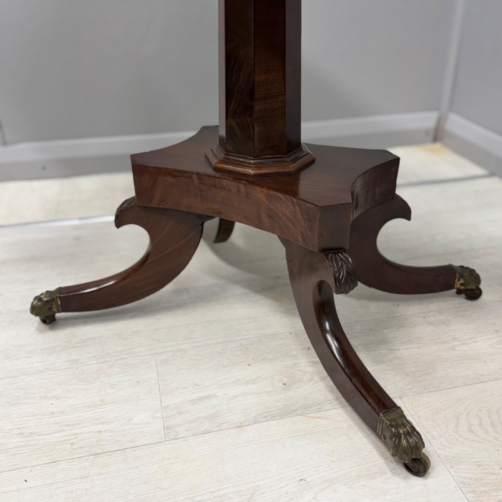 A Late Georgian dark mahogany fold-over side table featuring a beaded frieze, faceted pedestal base, and quadruped sabre legs with brass paw castors. View IV
