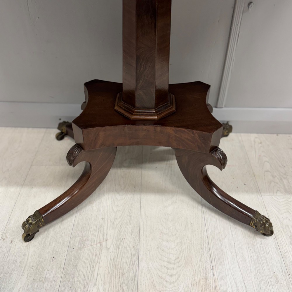 A Late Georgian dark mahogany fold-over side table featuring a beaded frieze, faceted pedestal base, and quadruped sabre legs with brass paw castors. View V