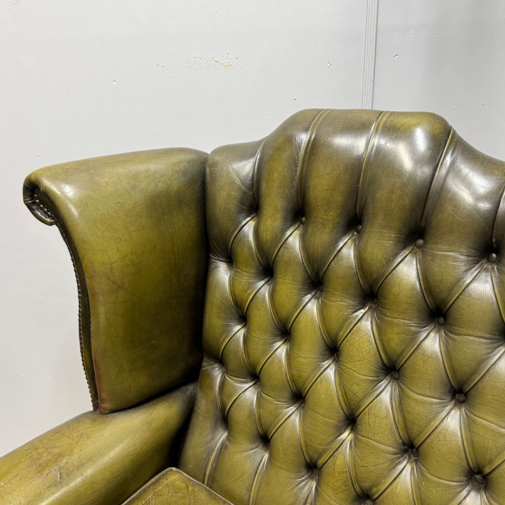 A two-seater high back sofa upholstered in deep-buttoned olive green leather with brass stud trimming and dark wooden cabriole legs. View II