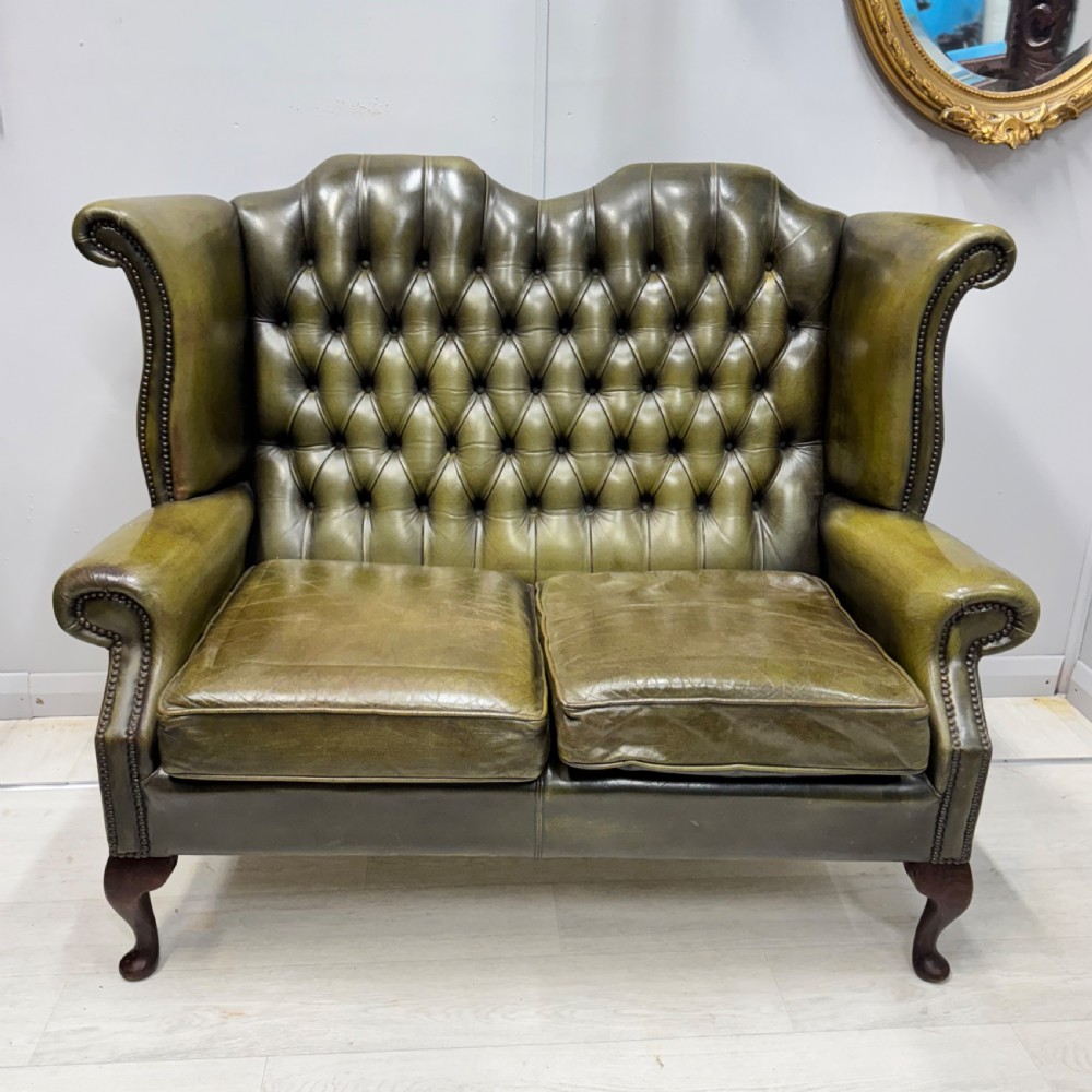 A two-seater high back sofa upholstered in deep-buttoned olive green leather with brass stud trimming and dark wooden cabriole legs. View III