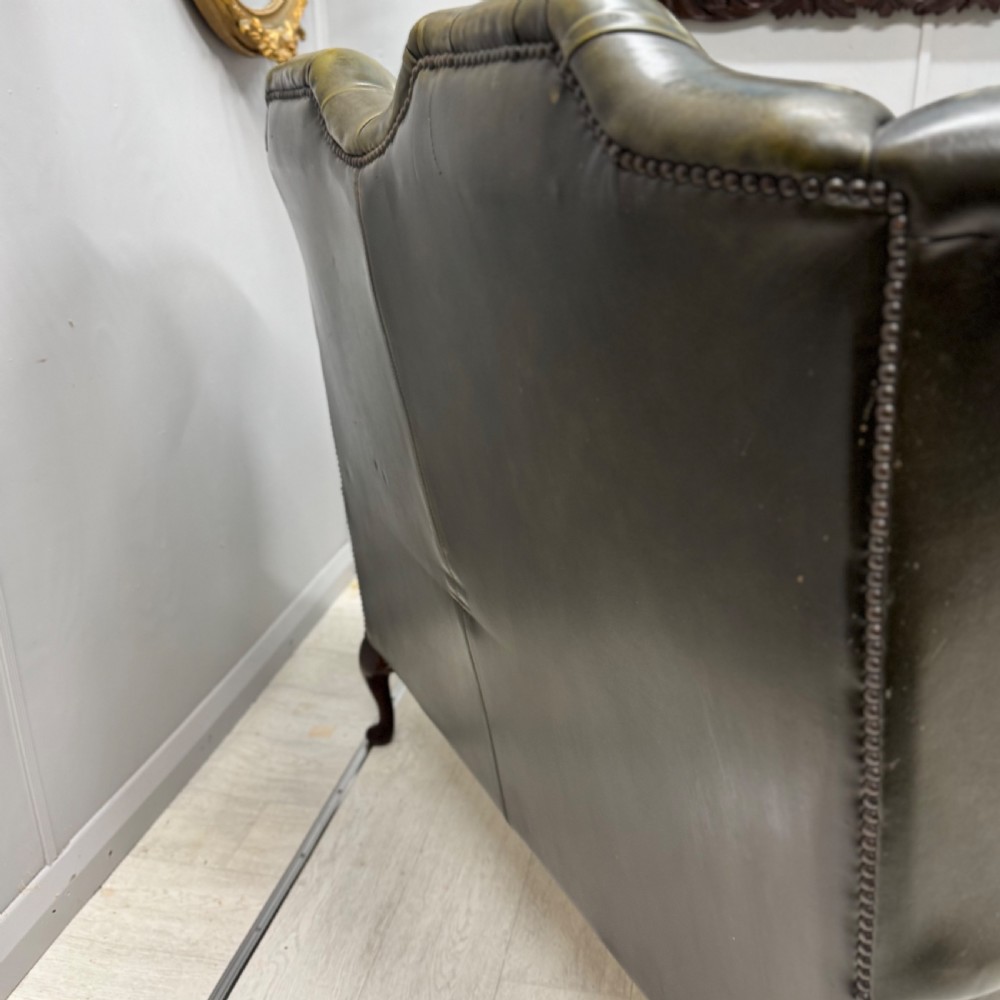 A two-seater high back sofa upholstered in deep-buttoned olive green leather with brass stud trimming and dark wooden cabriole legs. View VII