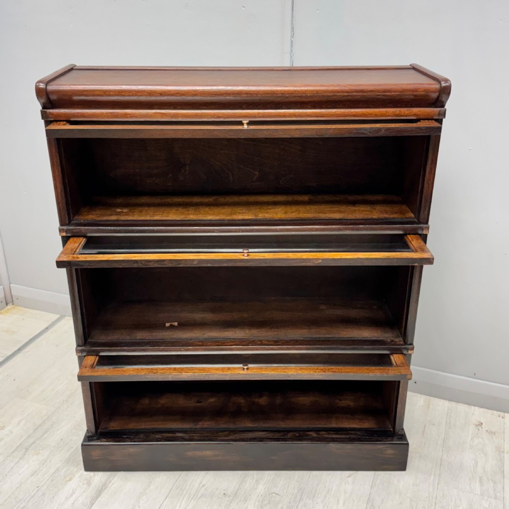 A three-tier oak Globe Wernicke stacking bookcase with glazed drop-down doors featuring small brass knobs. View II