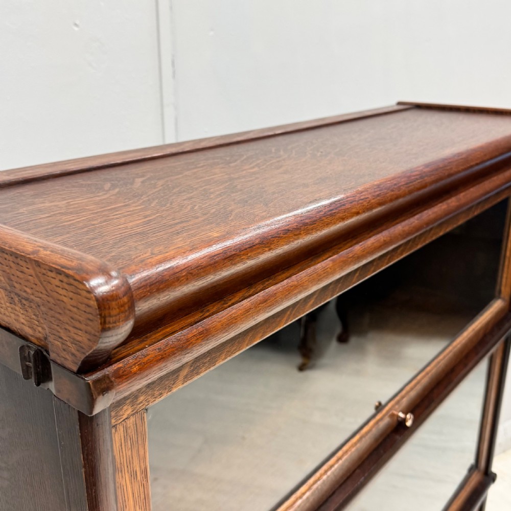 A three-tier oak Globe Wernicke stacking bookcase with glazed drop-down doors featuring small brass knobs. View III