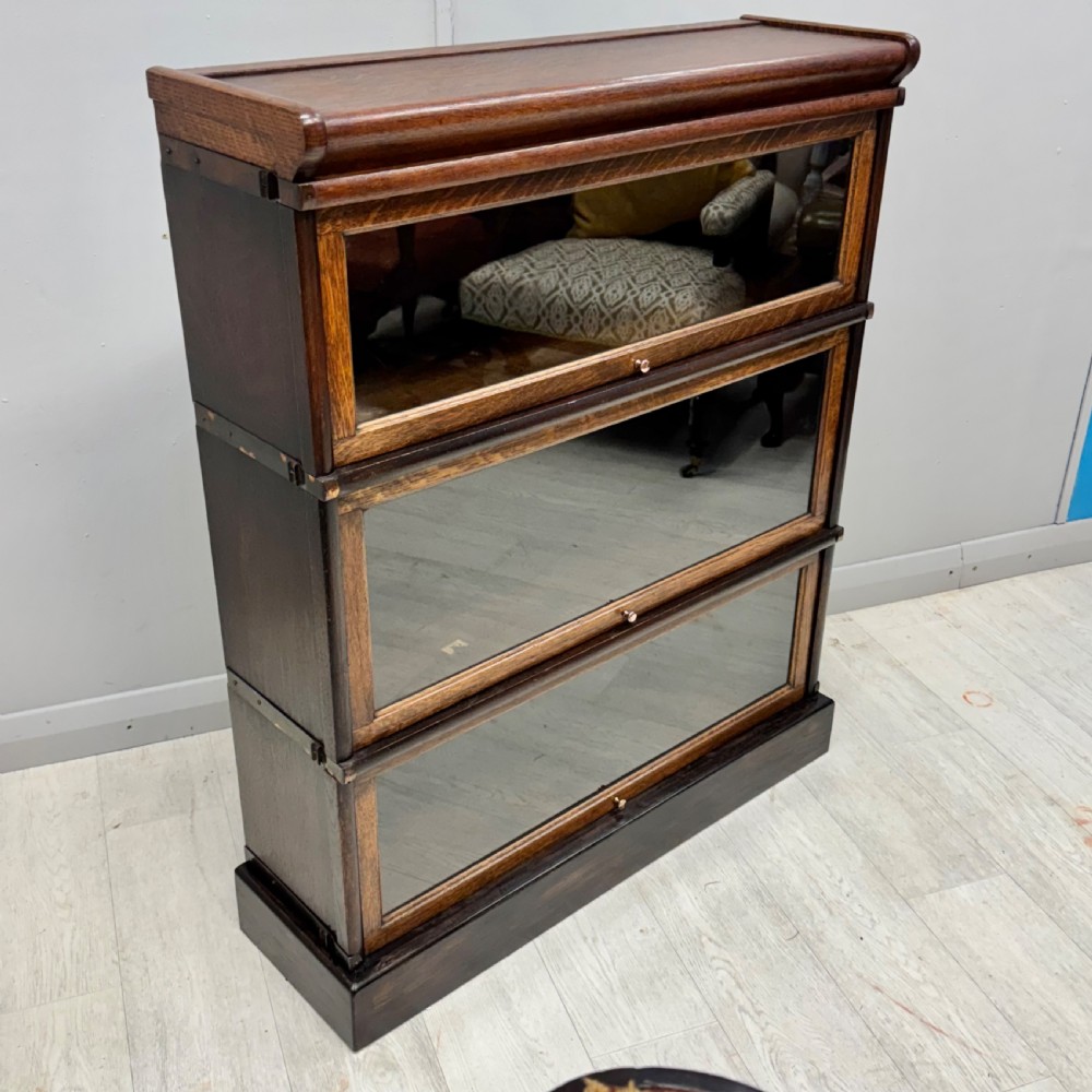 A three-tier oak Globe Wernicke stacking bookcase with glazed drop-down doors featuring small brass knobs. View V