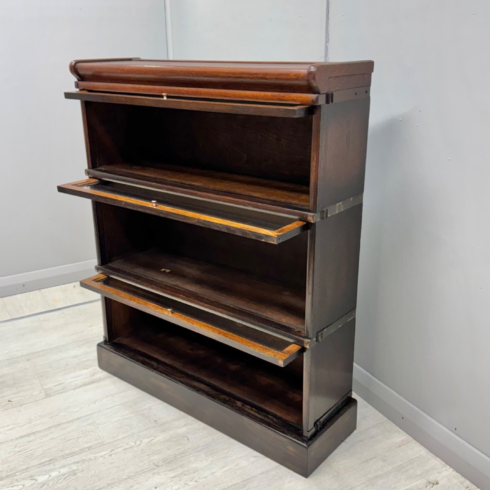A three-tier oak Globe Wernicke stacking bookcase with glazed drop-down doors featuring small brass knobs. View VI