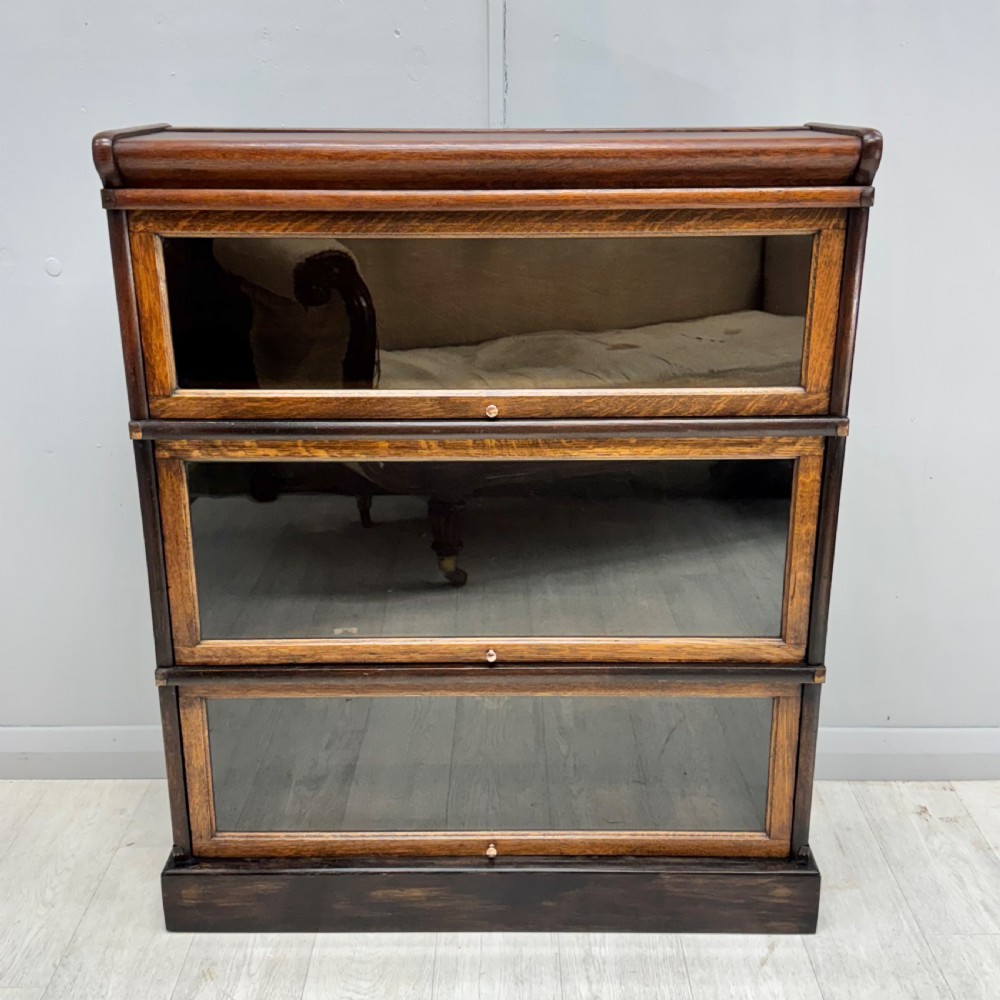 A three-tier oak Globe Wernicke stacking bookcase with glazed drop-down doors featuring small brass knobs. View VIII