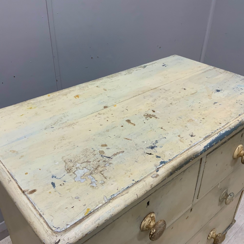 A 19th-century painted pine chest of drawers featuring two short over two long drawers, turned wooden knobs, turned bun feet, and a distressed cream painted finish. View II