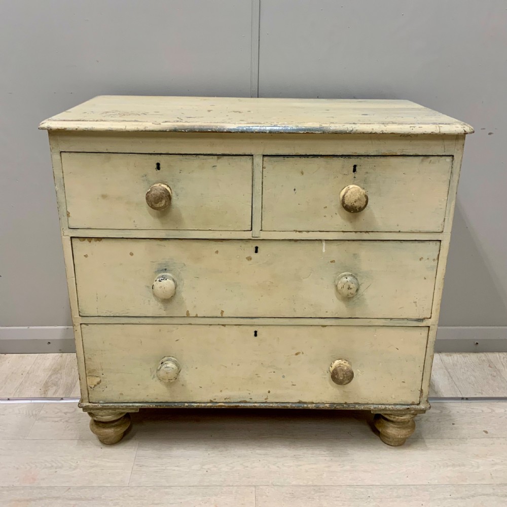 A 19th-century painted pine chest of drawers featuring two short over two long drawers, turned wooden knobs, turned bun feet, and a distressed cream painted finish. View III