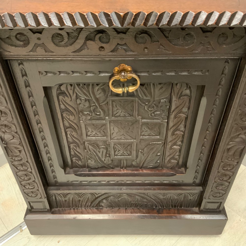 An Edwardian carved dark oak Purdonium coal box featuring a drop-front compartment, internal metal liner, and an included metal shovel with a wooden handle. View IV