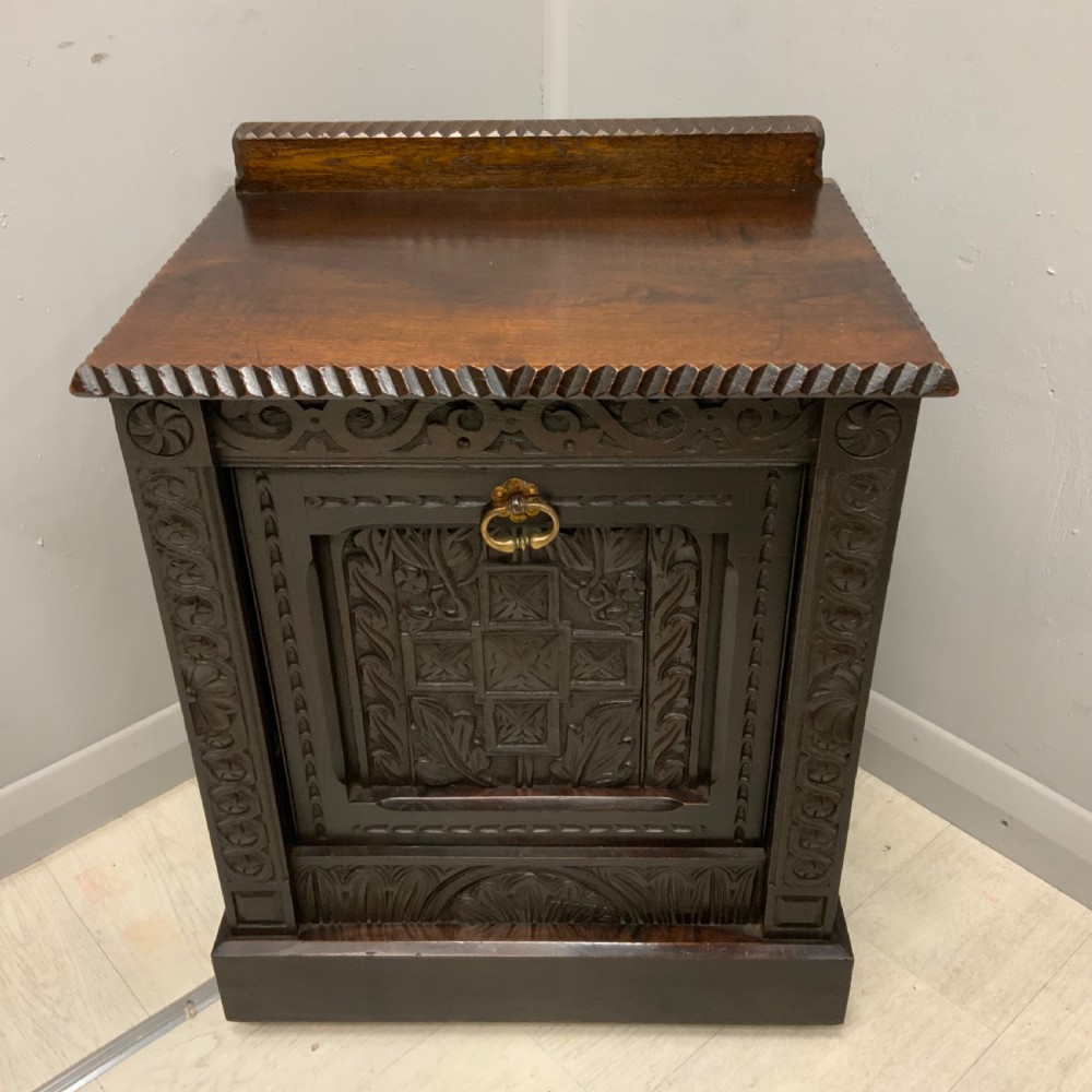 An Edwardian carved dark oak Purdonium coal box featuring a drop-front compartment, internal metal liner, and an included metal shovel with a wooden handle. View V