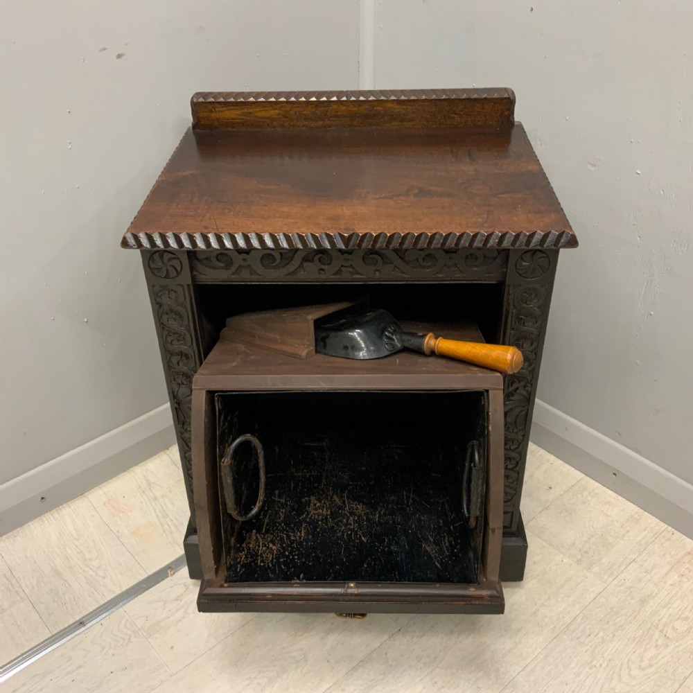 An Edwardian carved dark oak Purdonium coal box featuring a drop-front compartment, internal metal liner, and an included metal shovel with a wooden handle. View VI