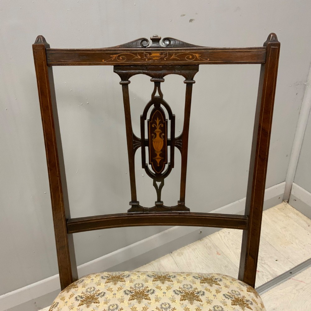 A pair of Edwardian inlaid mahogany nursing chairs featuring splats decorated with marquetry, padded upholstered seats, and turned front legs on castors. View II